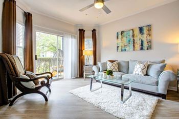 A living room with a grey couch, a wooden chair, and a white rug.